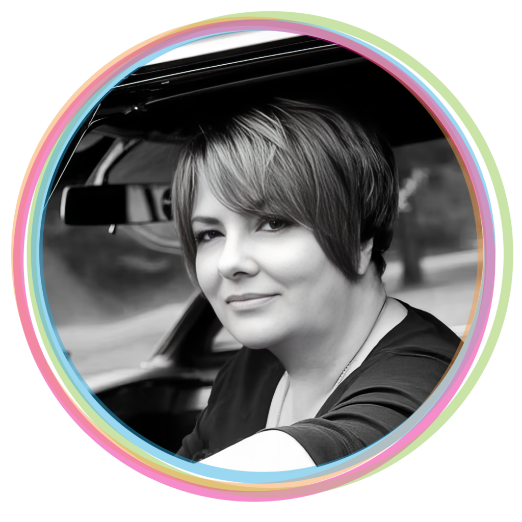 Black and white image of a woman with short hair sitting in a car looking at the camera.