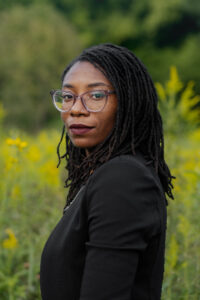 A woman wearing glasses and a black shirt with long black hair.