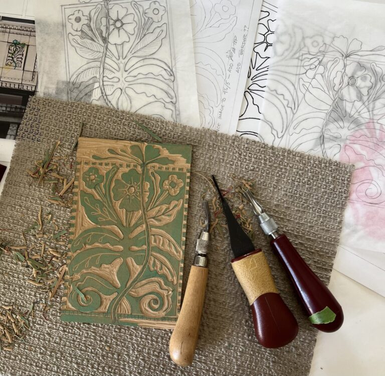 Woodcarving tools next to a woodcut of a floral design.